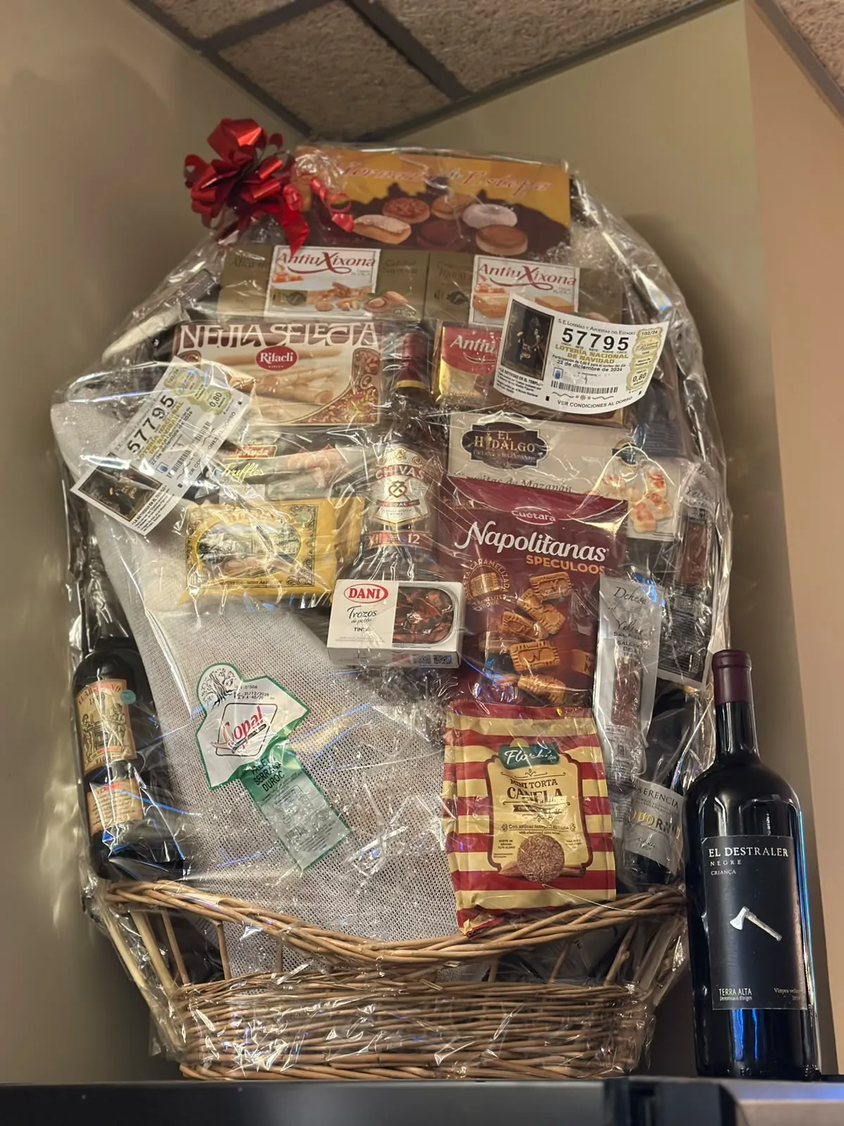 La panera de Nadal solidària muntada al restaurant: una gran cistella de vímet embolicada amb cel·lofana, plena de dolços de Nadal, galetes, conserves i ampolles de vi, amb un llaç vermell a dalt.